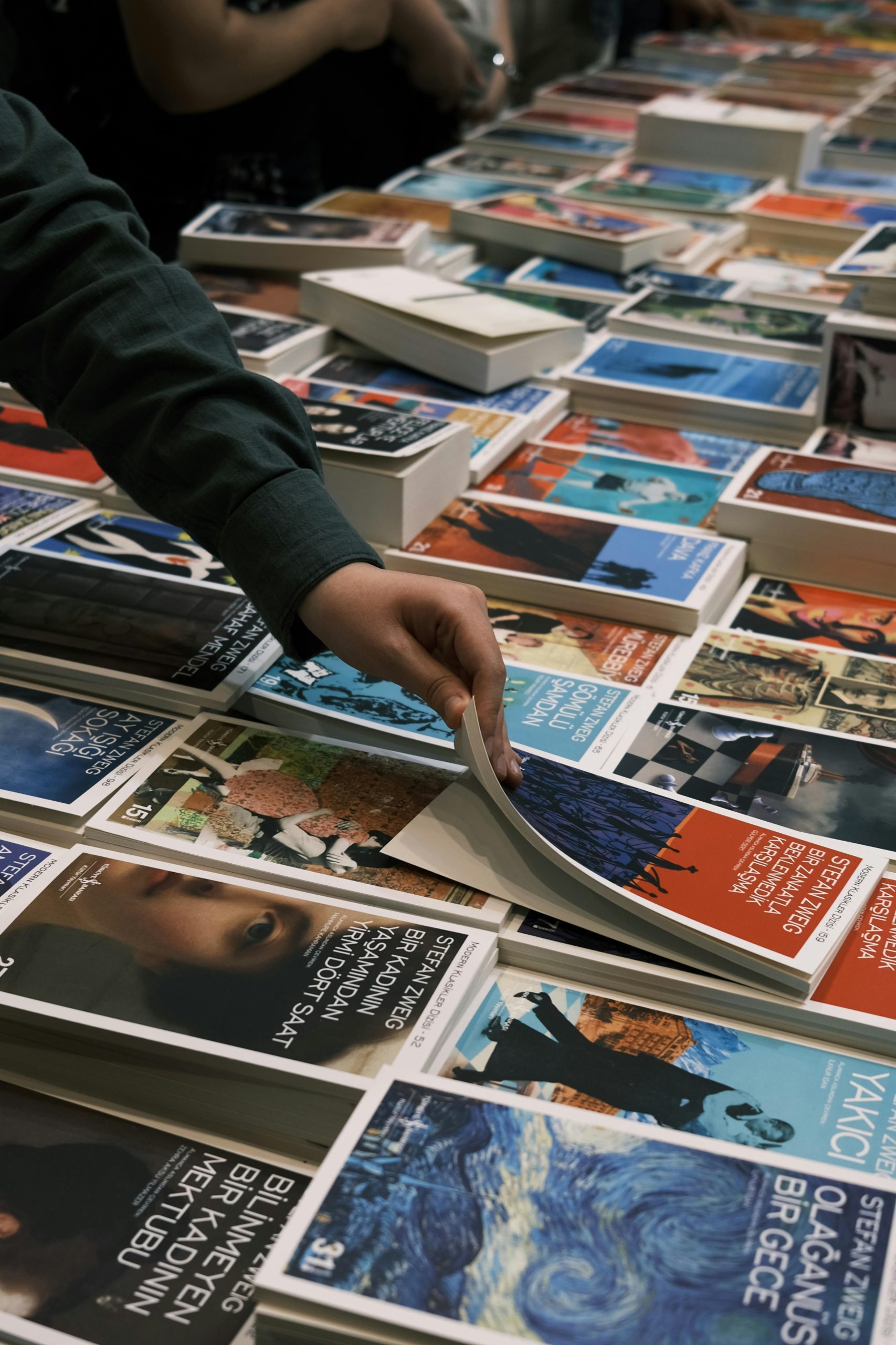 Person browsing books at a lively book sale in İzmit, Türkiye.